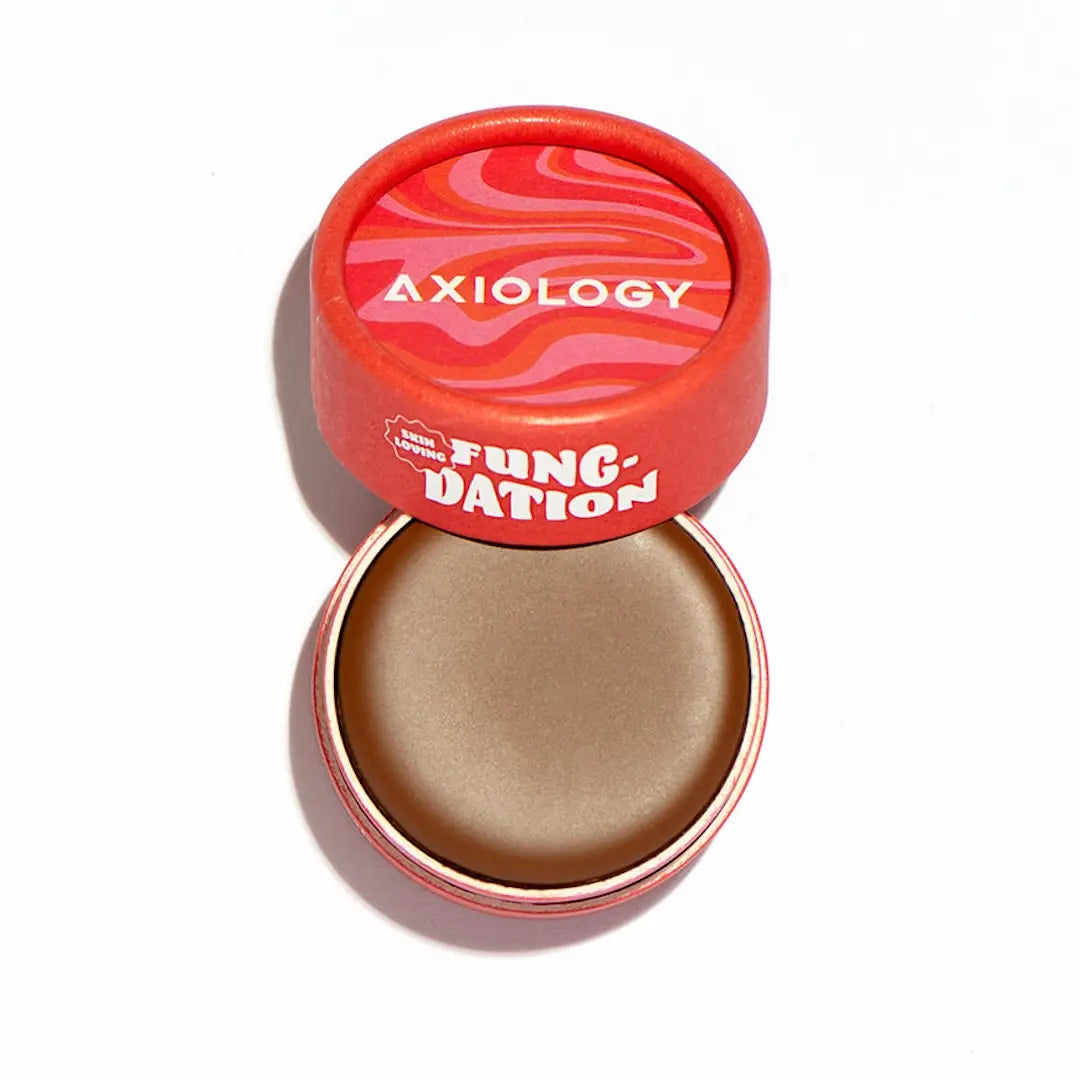 Axiology’s Fungdation Mushroom Foundation comes in a round red container with a pink-and-red wavy lid. Once opened, it reveals smooth brown cream for a natural satin finish.