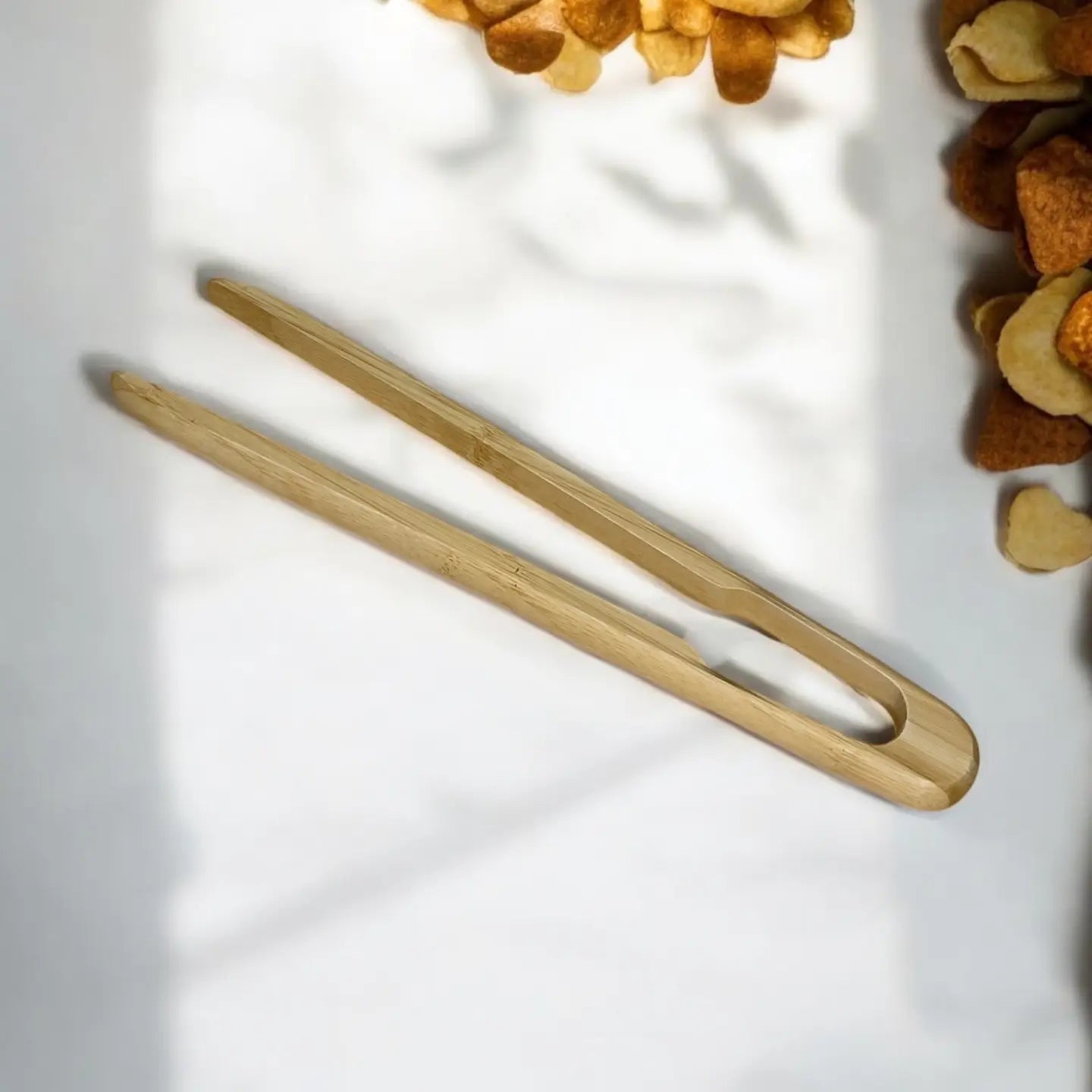 Two wooden tongs on a light surface with heart-shaped objects in the background.