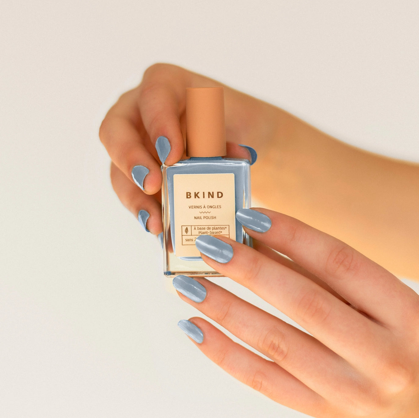 light blue nail polish with hands holding the bottle