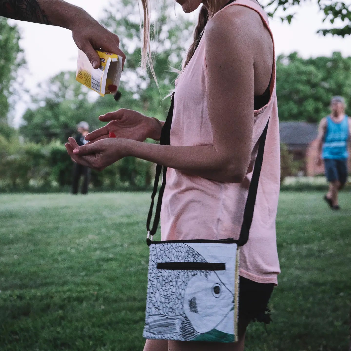 Person holding a small bag with a fish design outdoors