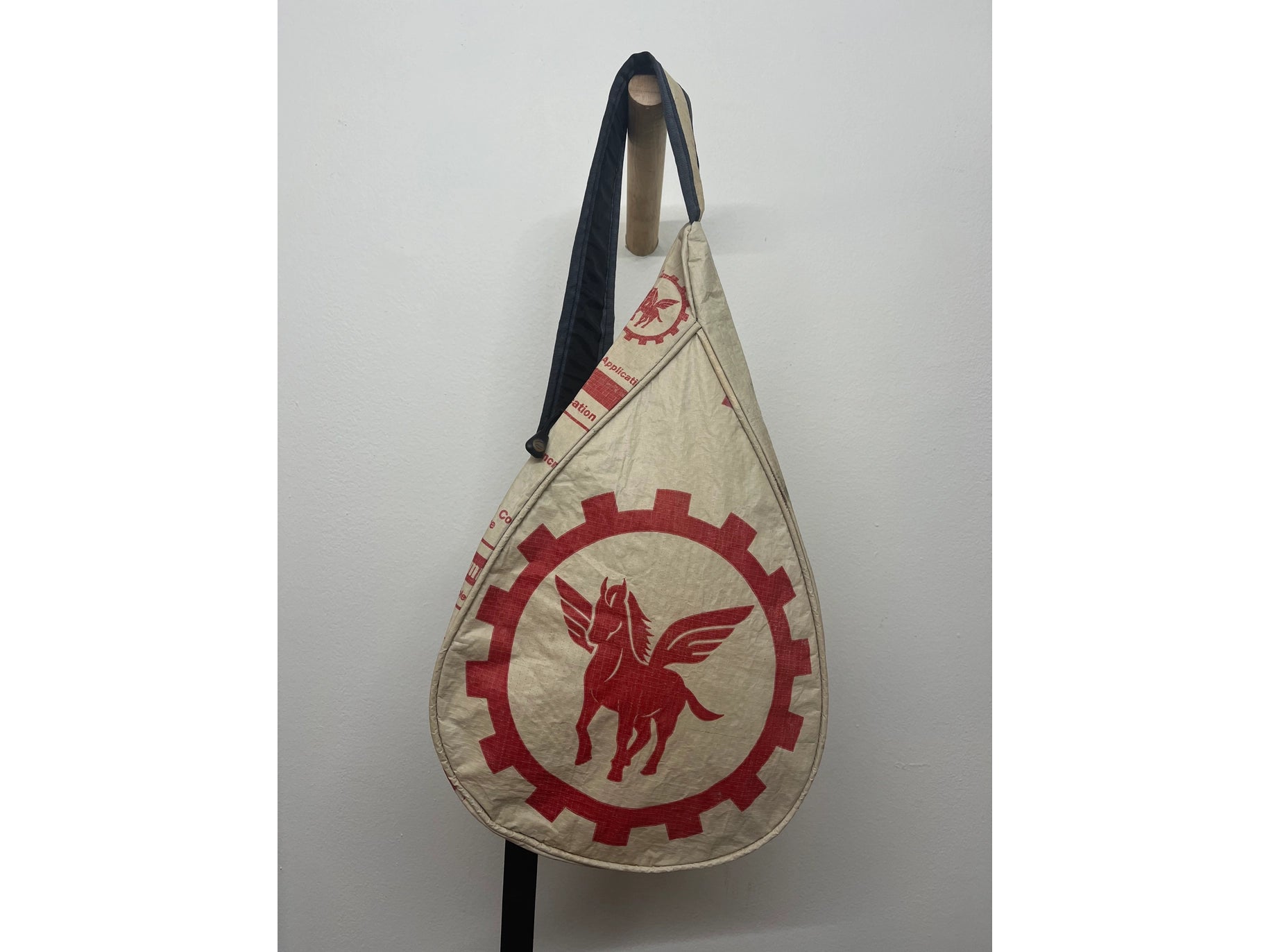Beige bag with red emblem featuring a winged horse on a white background