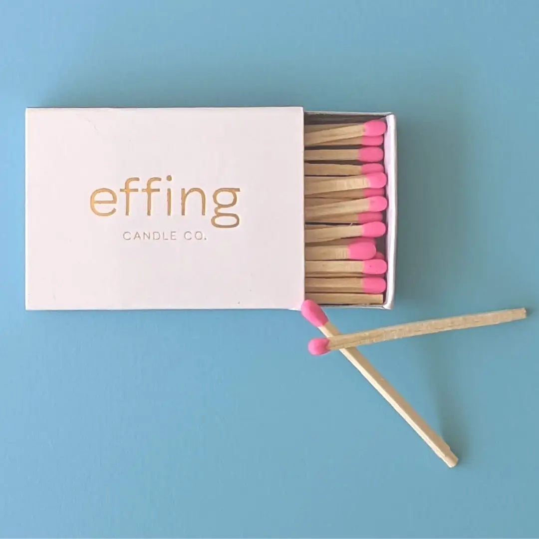 Matchbox with pink matches on a blue background, featuring &