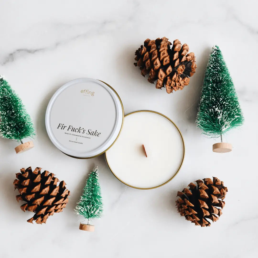 Candle with decorative trees and pinecones on a marble surface