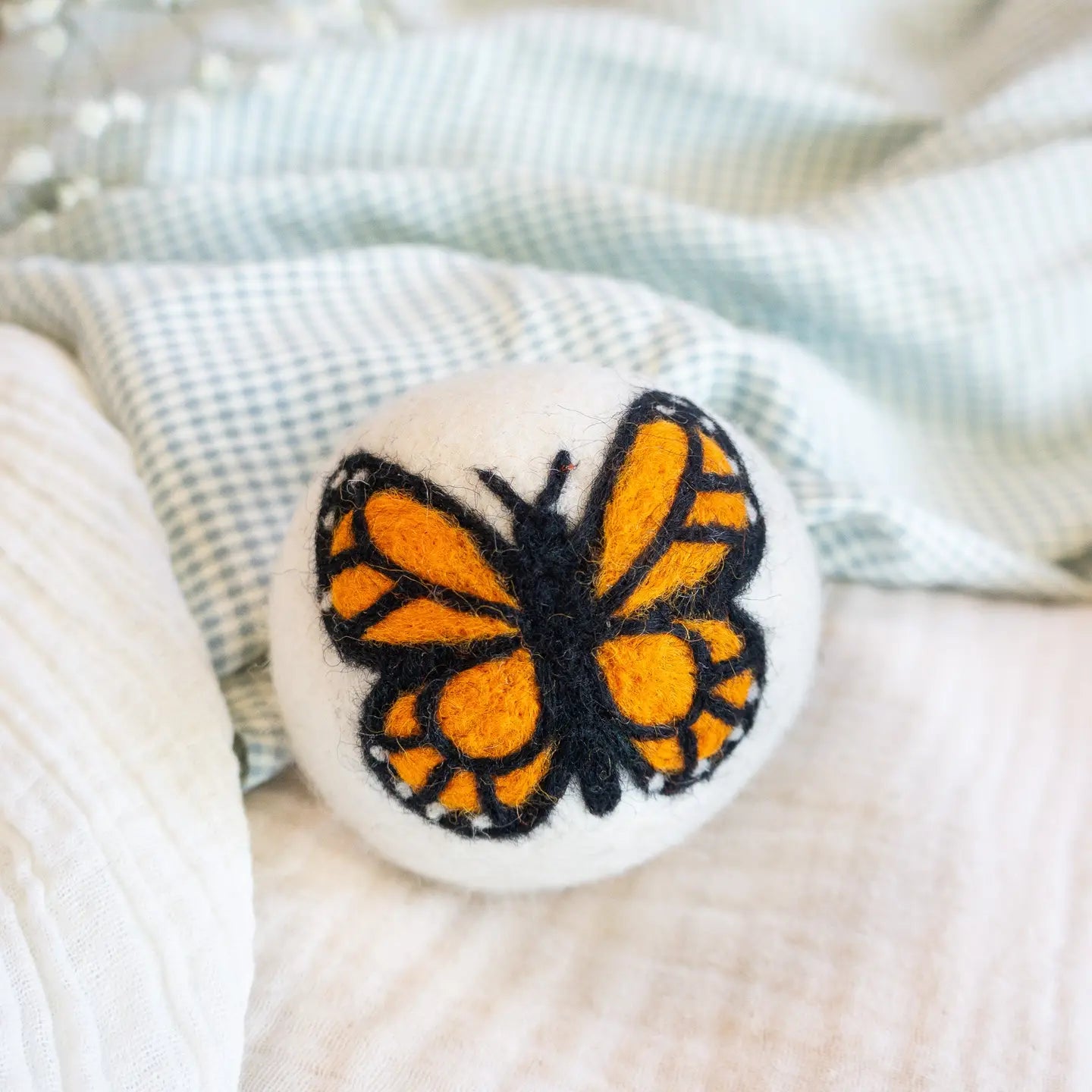 wool dryer ball Butterfly-shaped object with orange and black design on a textured surface