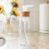 clear foaming soap dispenser with bamboo lid set on a kitchen counter