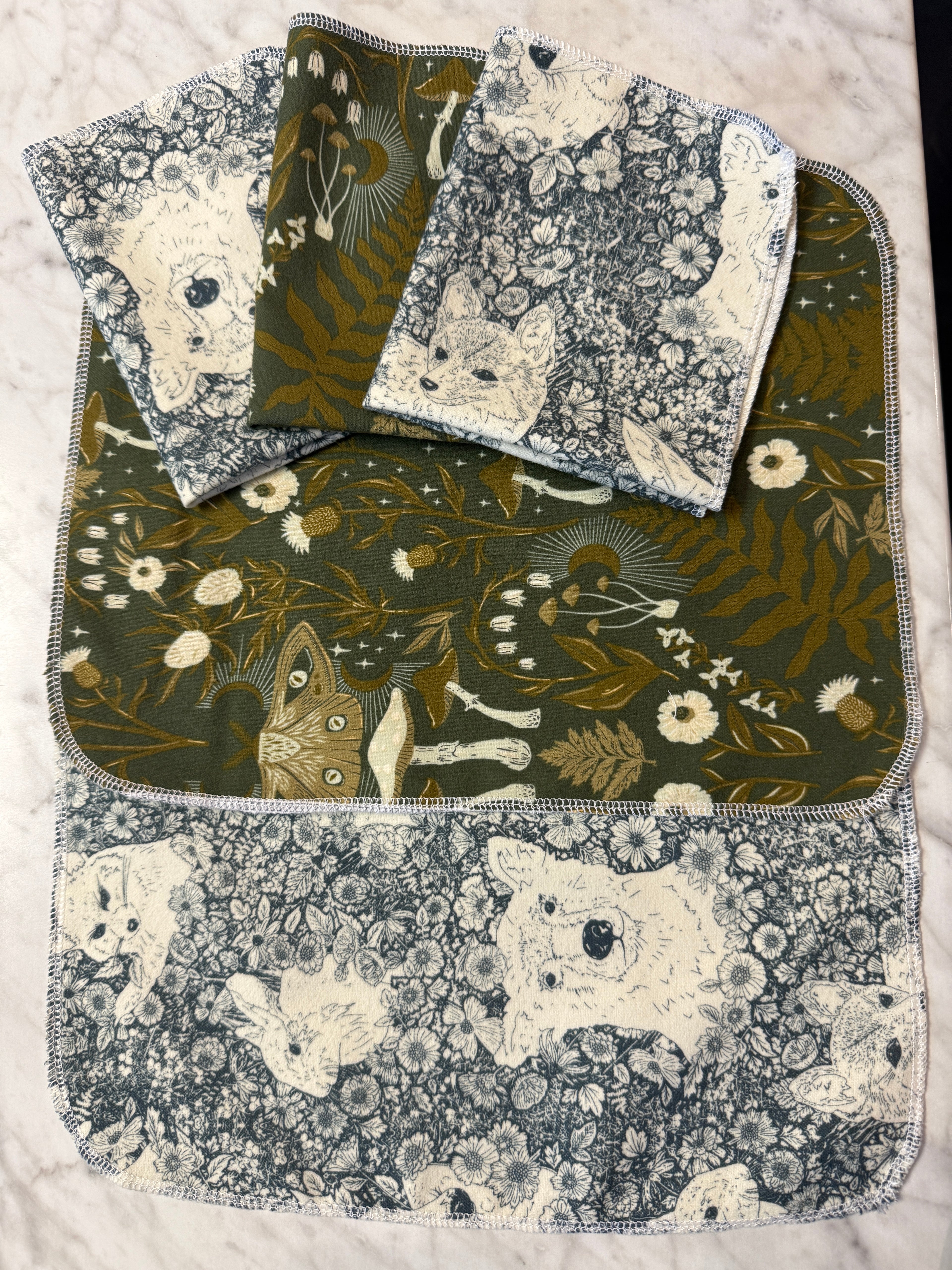 Set of fabric not paper towels with floral and nature-themed patterns on a marble surface.