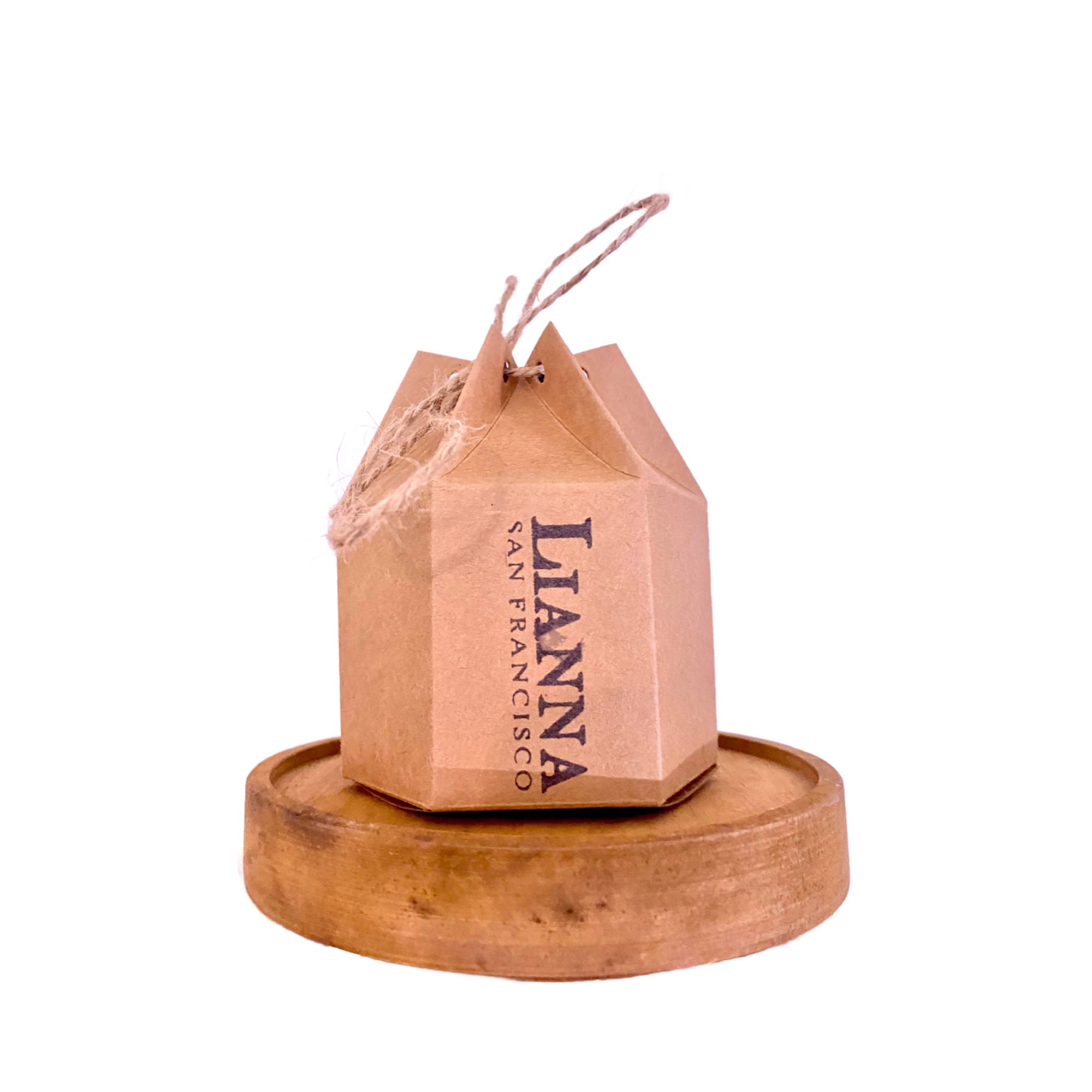 A brown, geometric Lianna box sits on a round wooden base. Designed for Lianna Handmade Bar Soap, it features a string handle on top and is perfect for gifting, standing out against a plain white background.
