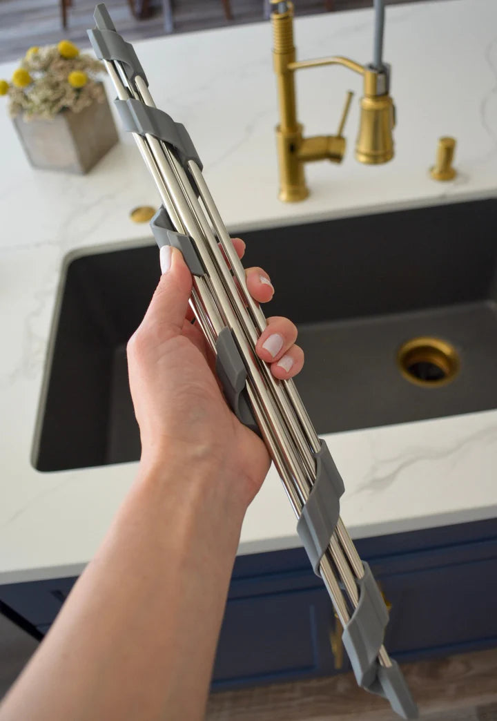Person holding a metal kitchen tool over a sink