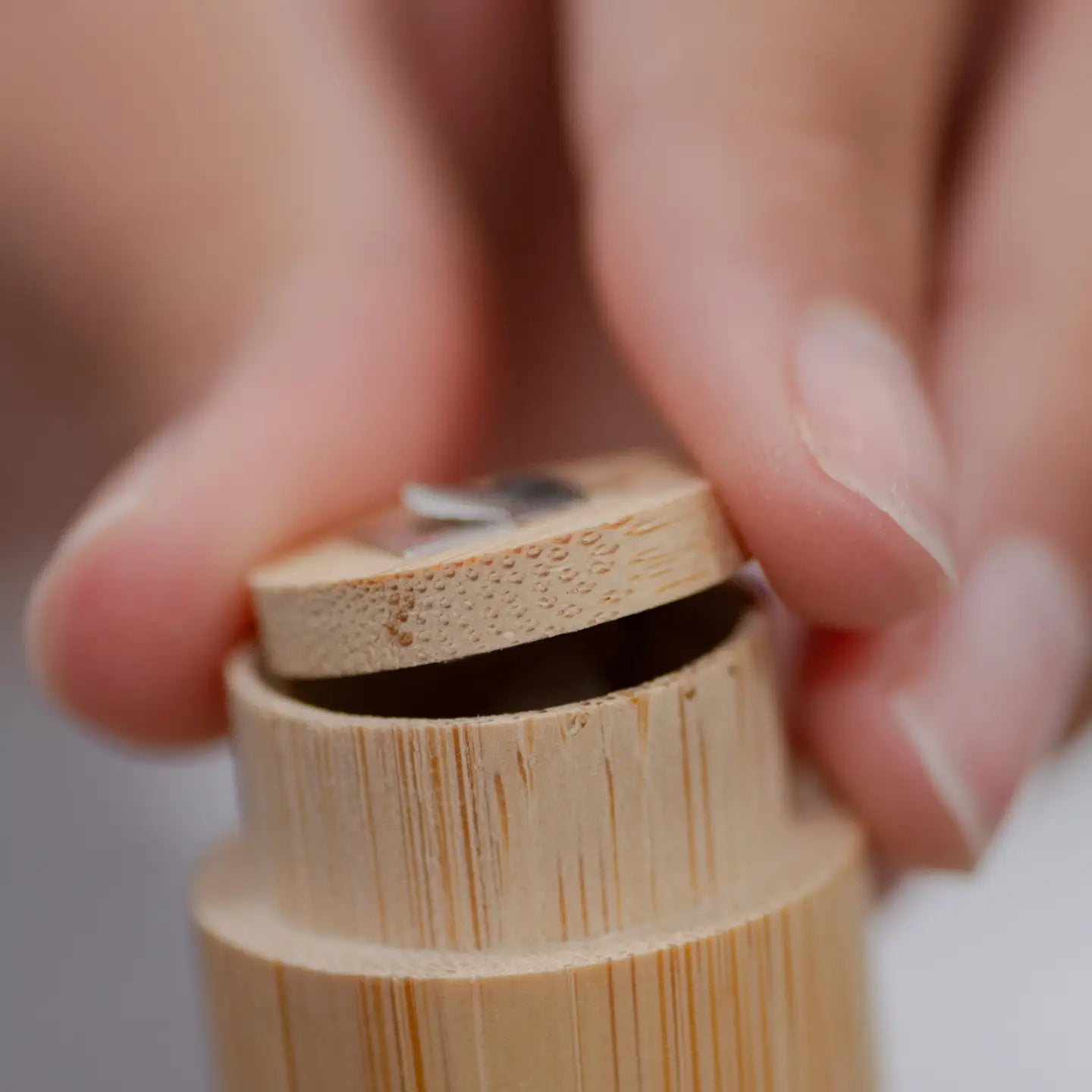 Close-up of a hand holding a bamboo floss case