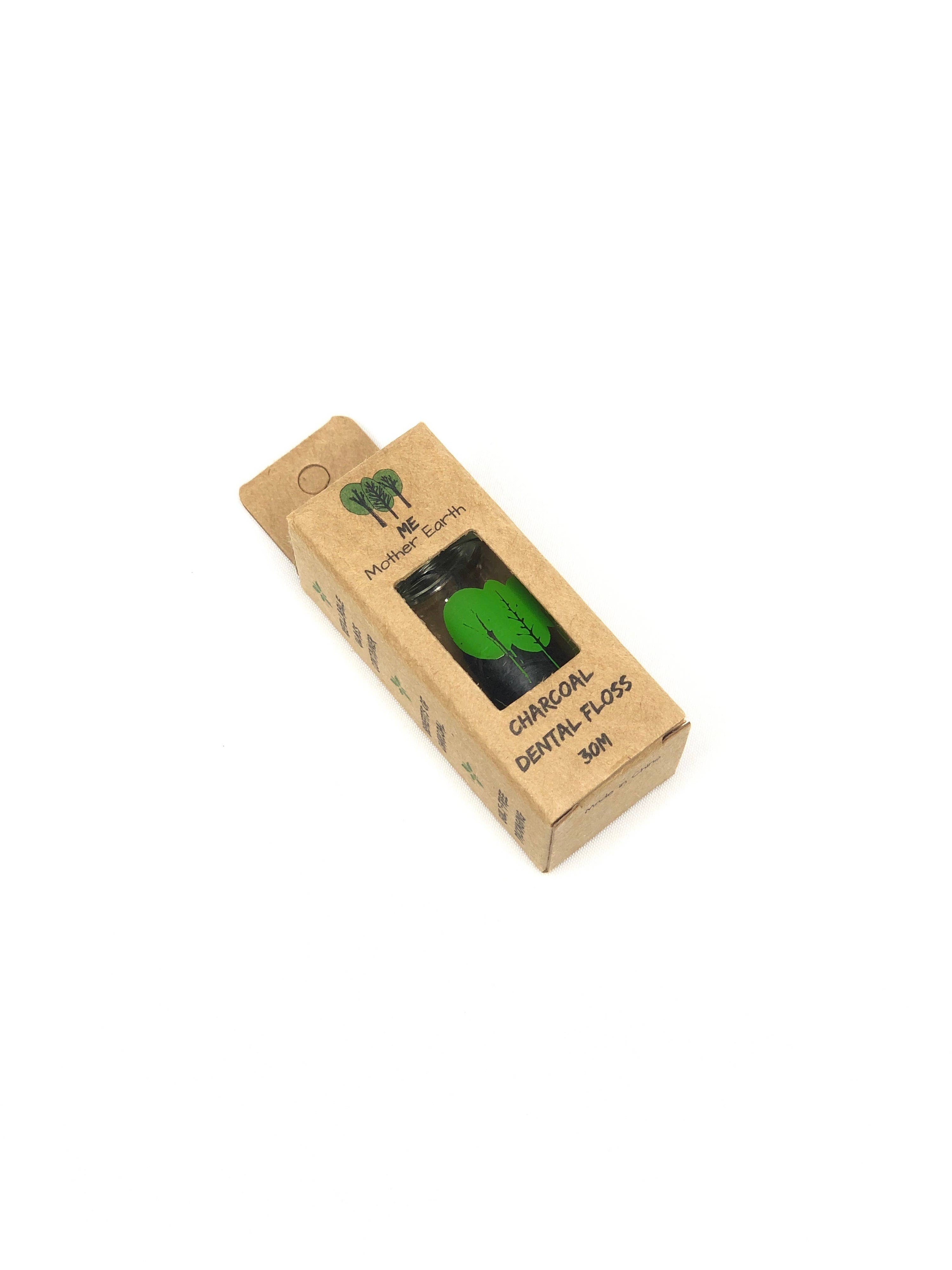 A cardboard package with a green label showing a picture of the dental floss inside, which is a glass container with bamboo charcoal dental floss.