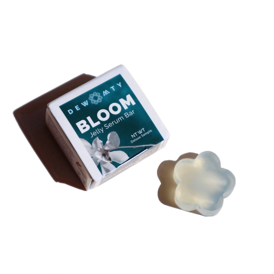 A translucent, flower-shaped Bloom Skin Serum Bar by Dewmighty sits beside its box on a white background—a hydrating, omega-rich jelly moisturizer ideal for skin barrier repair.
