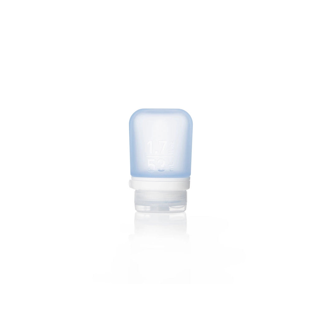 The Humangear GoToob+ is a small, translucent blue silicone travel bottle with a white flip-cap, standing upright. This refillable toiletry container has front measurement markings and is perfect as a leak-proof travel accessory.