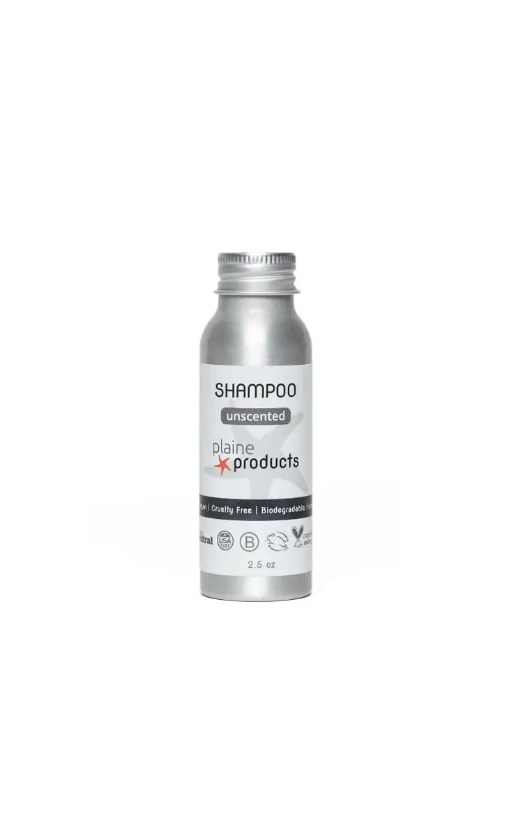 A 2.5 oz silver Plaine Products Shampoo bottle with a white label displays vegan, cruelty-free, and biodegradable icons; it’s refillable and made by Plaine Products.