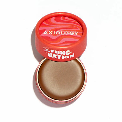 Axiology’s Fungdation Mushroom Foundation comes in a round red container with a pink-and-red wavy lid. Once opened, it reveals smooth brown cream for a natural satin finish.