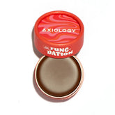 An open, round red container labeled "Axiology Fungdation Mushroom Foundation" with a swirled pink-red lid reveals a neutral-toned cream foundation inside.