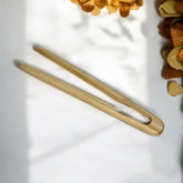 Two wooden tongs on a light surface with heart-shaped objects in the background.