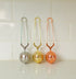 tea strainers lined up against white tile in steel, gold, and rose gold