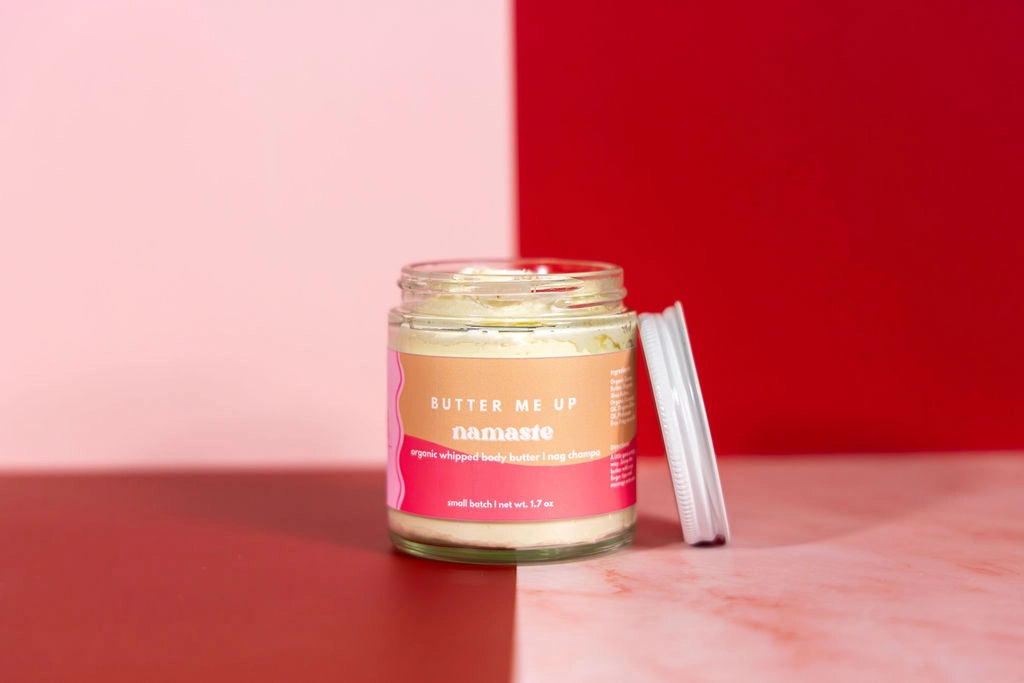Jar of namaste body butter with pink label on a red and pink background
