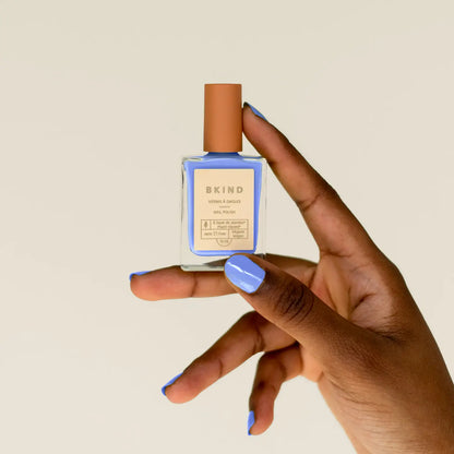 bkind nail polish in bright blue with hand holding the bottle