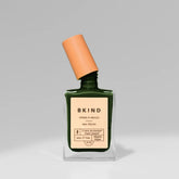 Green nail polish bottle with orange cap on a gray background
