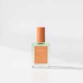 A glass bottle of BKind Nail Polish by BKind features light green polish and an orange cap, displayed on a white surface with a soft shadow.
