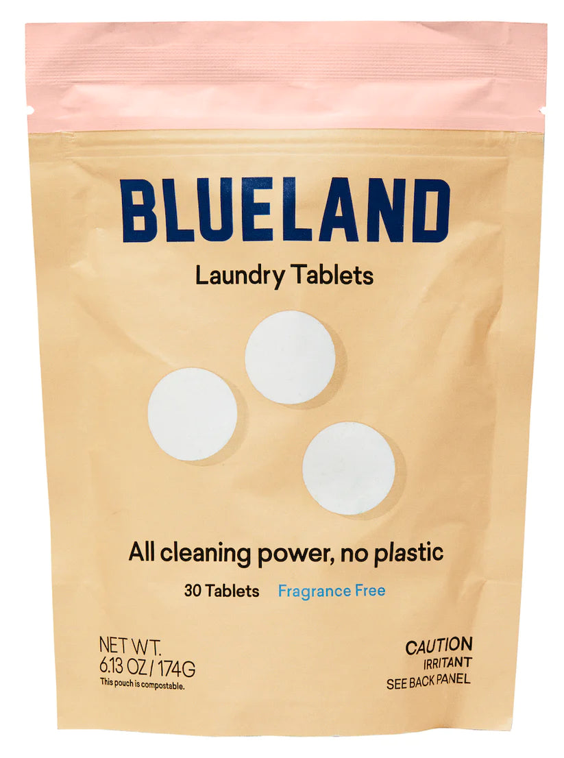 A beige and pink resealable pouch labeled Blueland Laundry Tablets, featuring 30 fragrance-free, plastic-free tablets made with clean ingredients. Includes caution for irritants. Three white tablets illustrated on the packaging.
