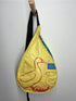 Yellow sling bag with duck design hanging on a white wall