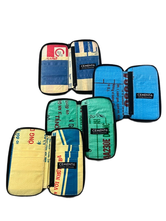 Four colorful Zipped Clutch pouches by Cement6, made from recycled cement bags, are shown open with various compartments in blue, yellow, red, and green—each a bold statement in sustainable fashion.