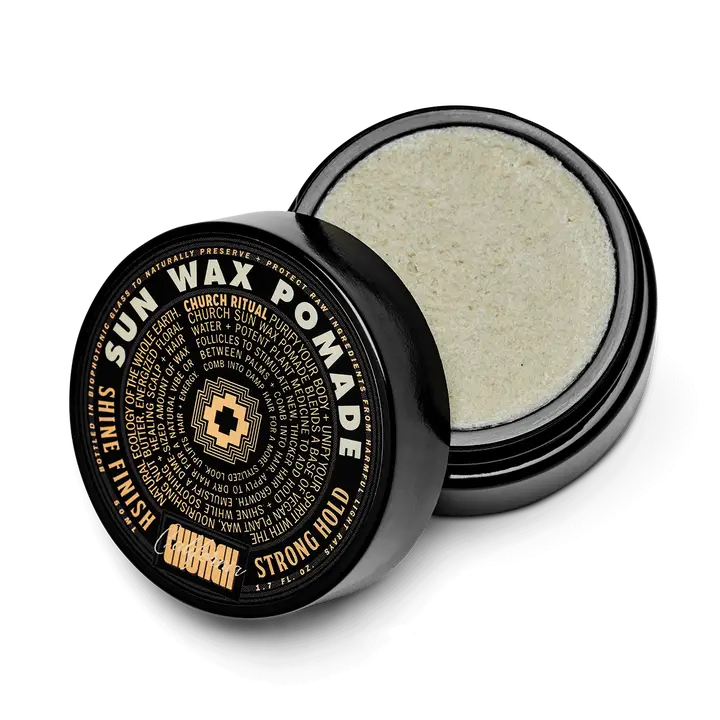 A black round container of Curch California Sun Wax Pomade - Strong Hold sits with its lid partially off, showing the light wax inside. The lid has bold gold and white lettering highlighting its strong hold and shine finish.