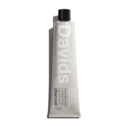 A tube of David’s Toothpaste by David’s in a minimalist white package with black cap, labeled charcoal, natural whitening, fluoride-free, sulfate-free, anti-plaque, and fresh breath.