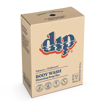 A beige box of Dip Body Wash Bars in Tobacco + Driftwood displays product details, eco-friendly icons, and blue/red Dip branding on the front. Net weight: 5.8 oz (164g).
