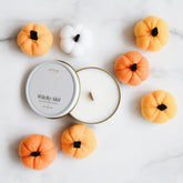 Candle with decorative pumpkins on a light background
