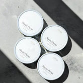 Four white containers with labels on a concrete surface