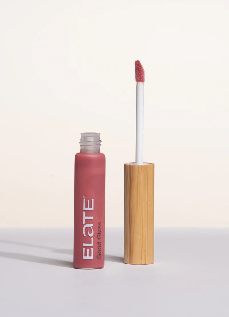 Lip gloss with wooden applicator and pink shade on a light background