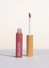 Lip gloss with wooden applicator and pink shade on a light background