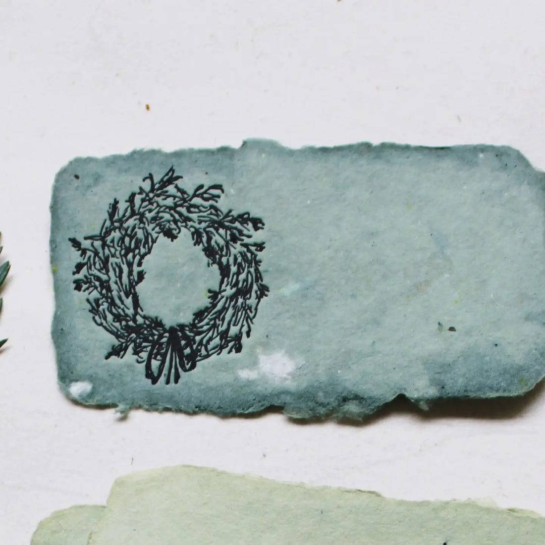 Handmade paper with a black wreath design on a white background