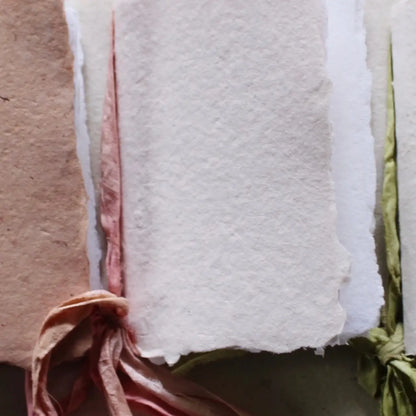 Close-up of a textured white fabric with pink and green edges on a neutral background