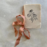 Small notebook with floral design and ribbon on a textured surface