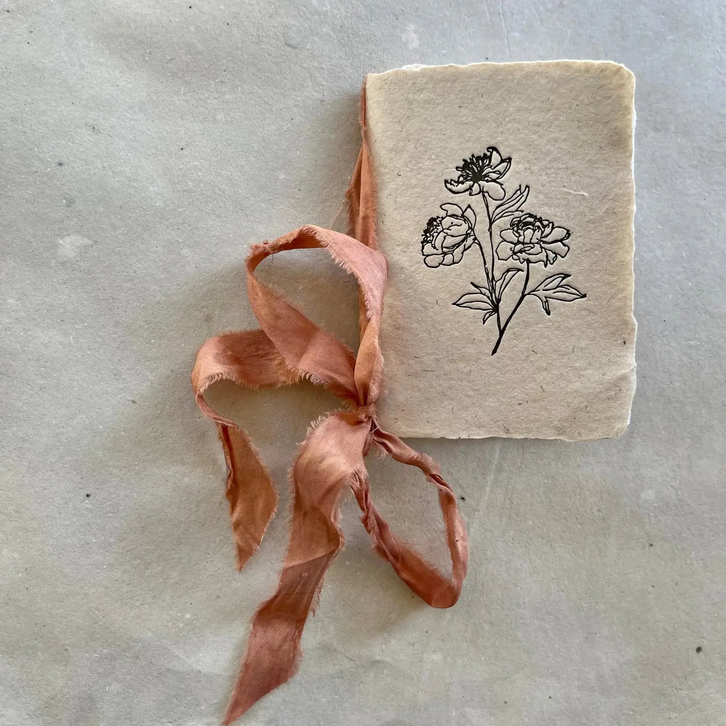 Small notebook with floral design and ribbon on a textured surface