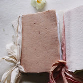 Textured pink fabric with tassels and a white flower on a light background