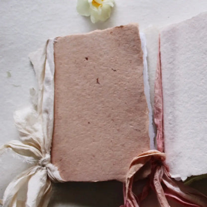 Textured pink fabric with tassels and a white flower on a light background