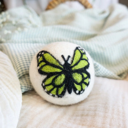 White dryer ball with green butterfly design on a textured surface