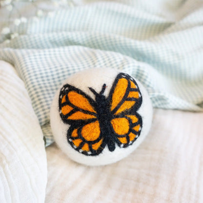 wool dryer ball Butterfly-shaped object with orange and black design on a textured surface