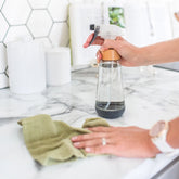 spray bottle with hands cleaning with a green towel