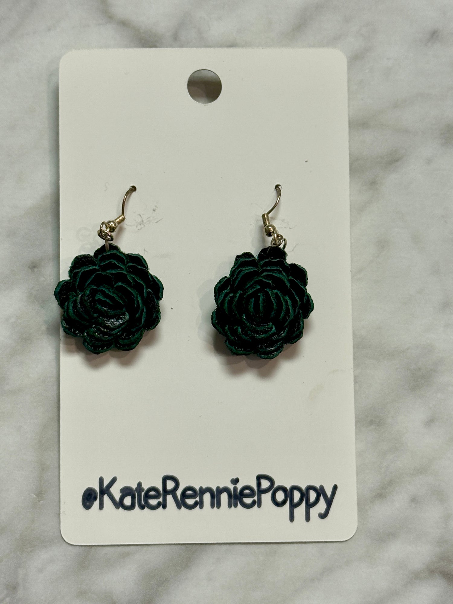 Black rose-shaped earrings on a &