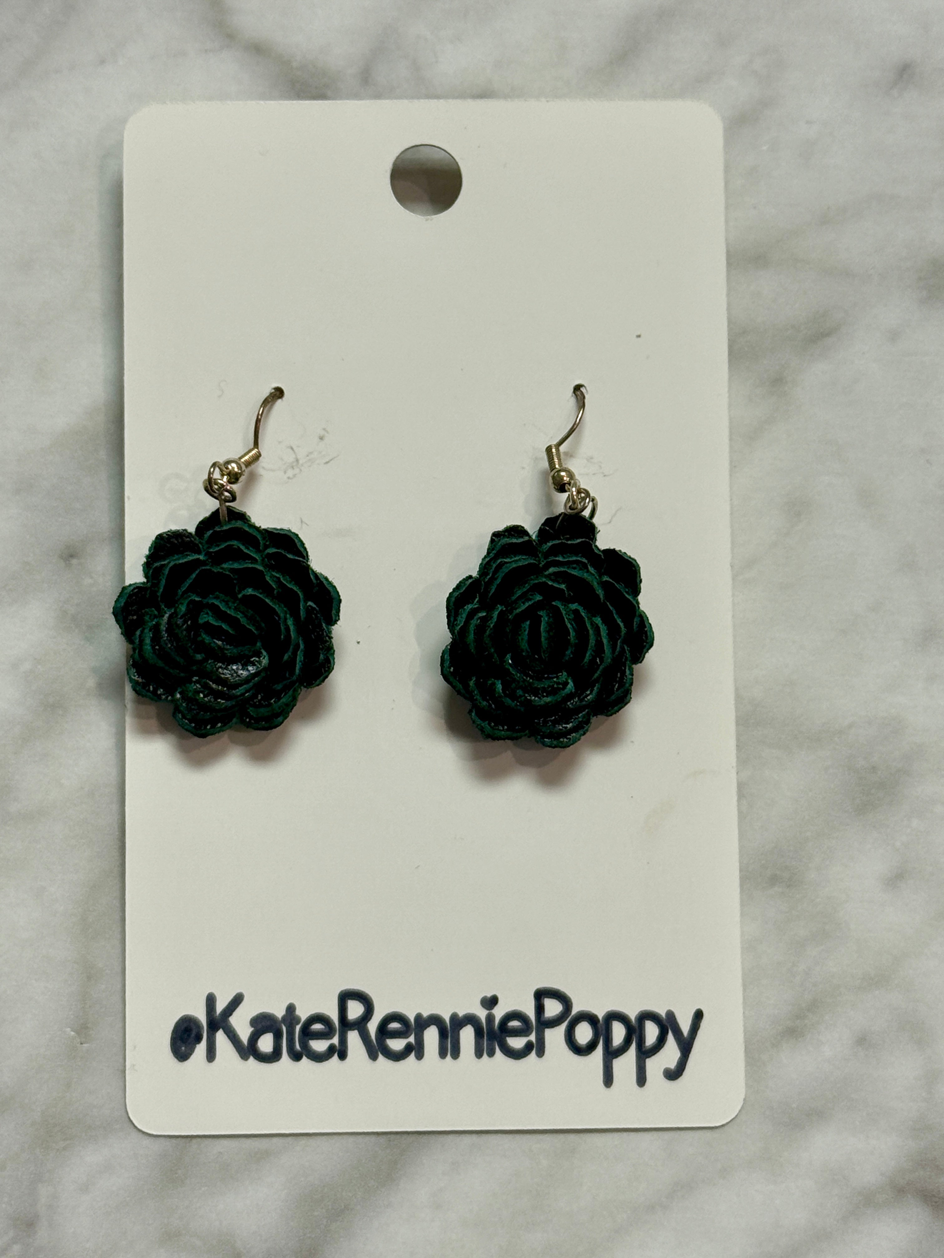 Black rose-shaped earrings on a &