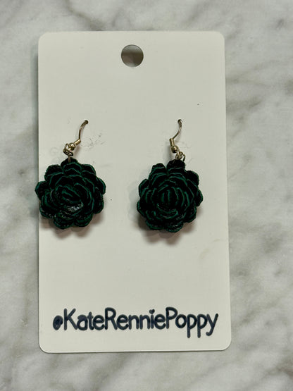 Black rose-shaped earrings on a &