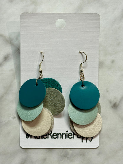 Colorful layered disc earrings on a branded card against a marble background