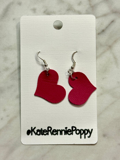 Red heart-shaped earrings on a white card with &