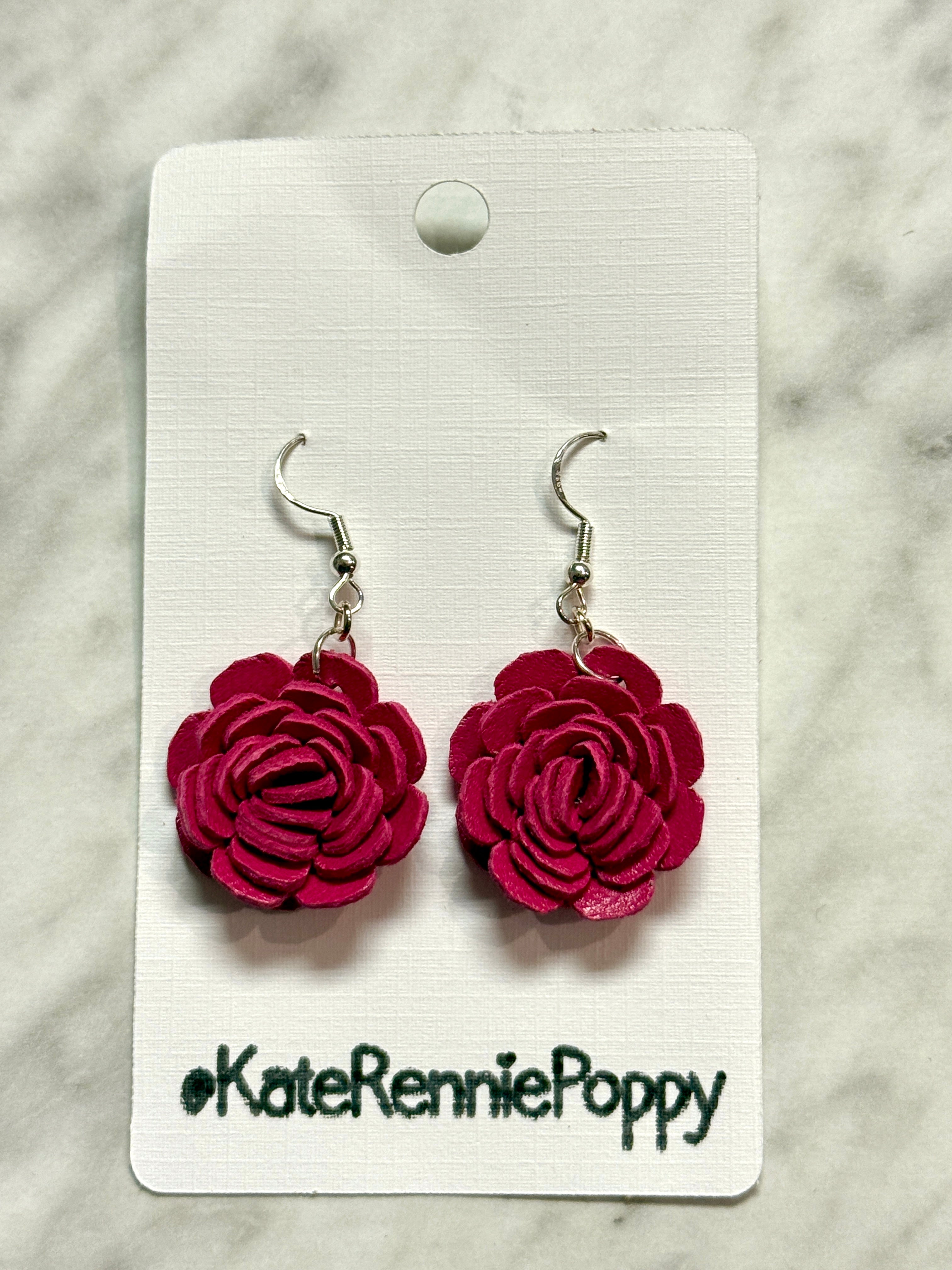 Pink rose-shaped earrings on a white card with &
